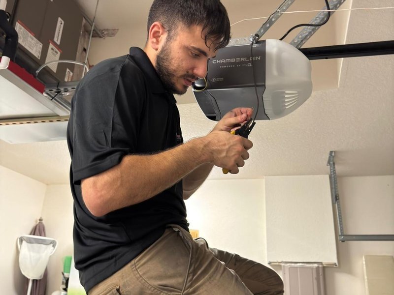 Technician adjusting a ceiling-mounted garage door opener unit