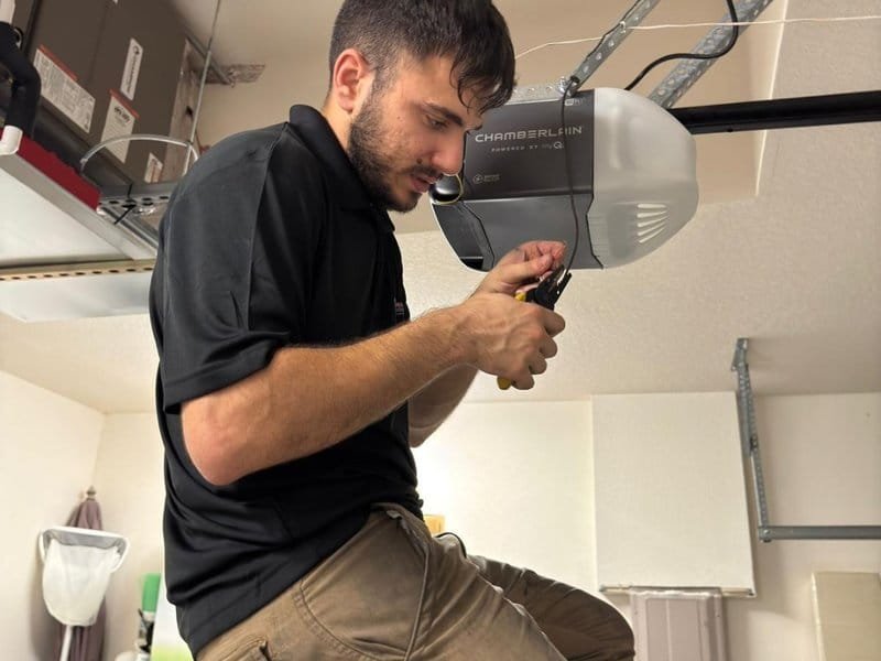 Technician adjusting a ceiling-mounted garage door opener unit