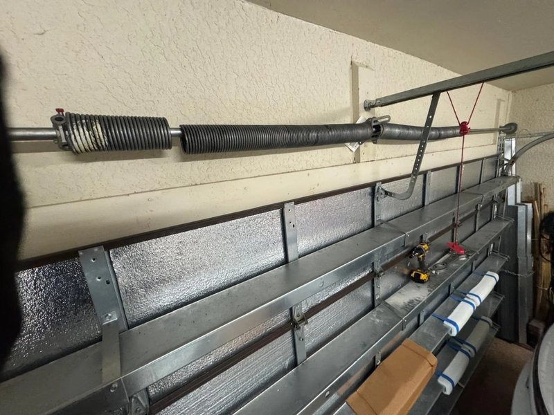 Torsion spring and shaft above an insulated sectional garage door