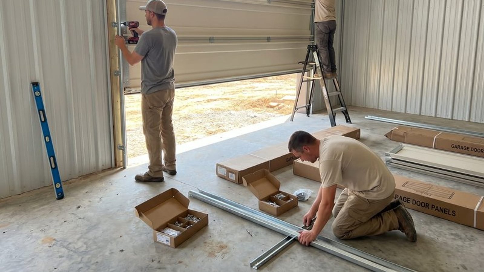 Door sections and tools laid out while technicians fit the track